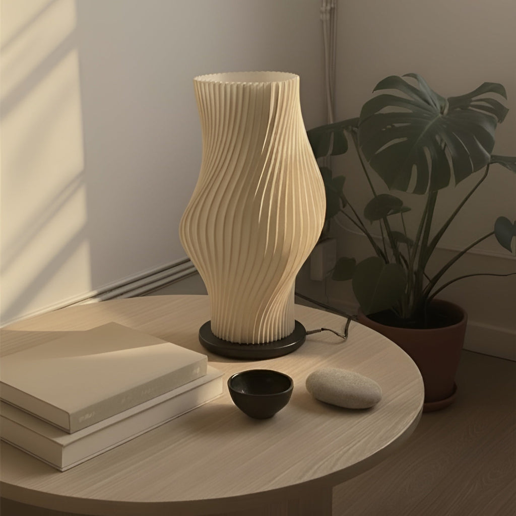 Beige textured lamp on a wooden table with books and a plant in the background